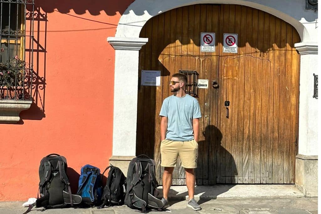 A man in t-shirt and shorts in front of a large wooden door in Antigua Guatemala