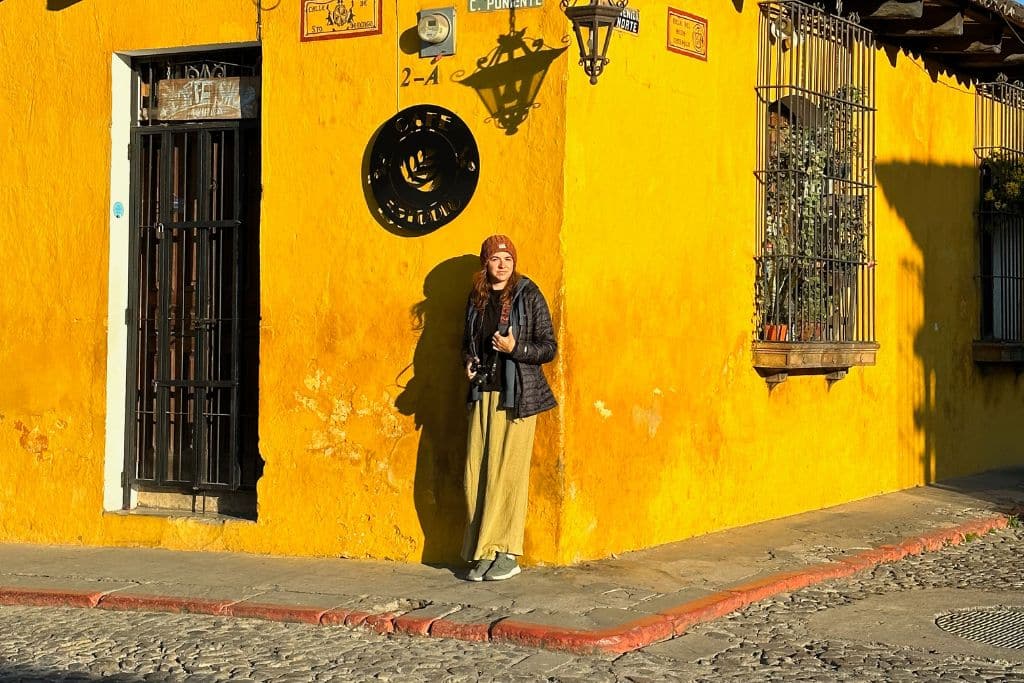 A girl stood in front of a picturesque yellow building in Antigua Guatemala