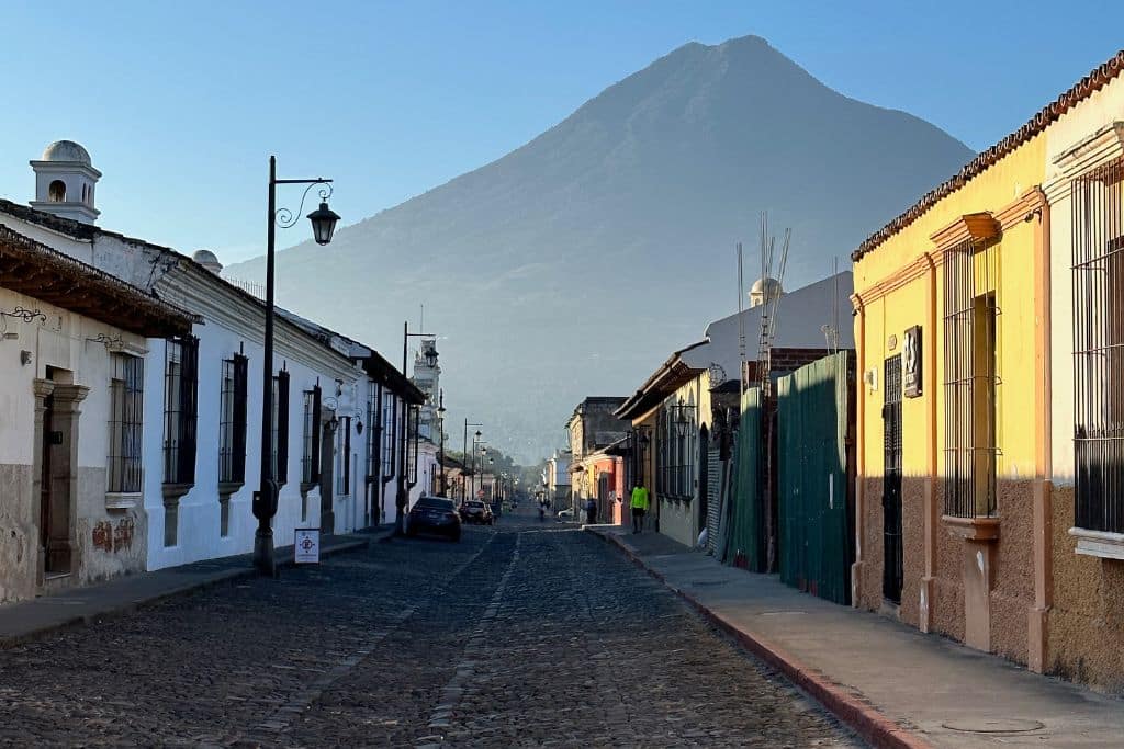 One of the many cobblestone streets of Antigua Guatemala, with a volcano in the background