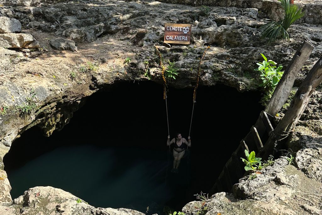 a girl sitting on a swing in cenote Calavera in Tulum, Mexico