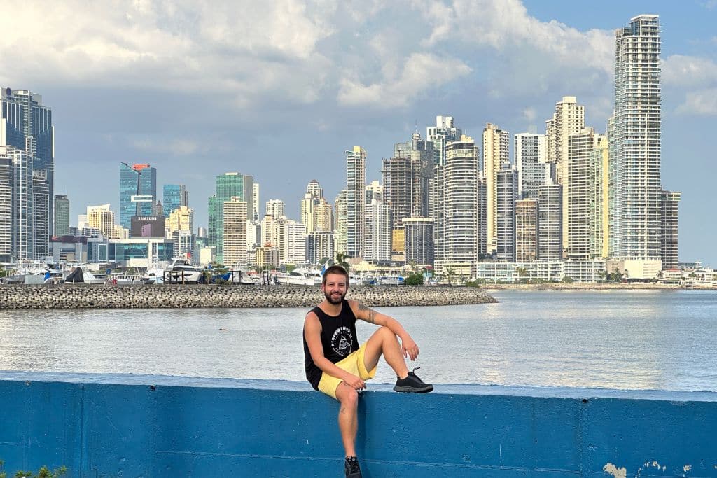 Man posing on a wall with the skyline of Panama City in the background. Is Panama worth to visit?