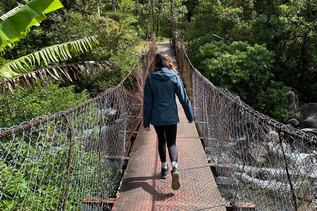 A girl crossing a suspension bridge over a river in Boquete, Panama