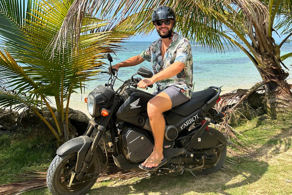 Man posing on a scooter with beautiful Caribbean water in the background