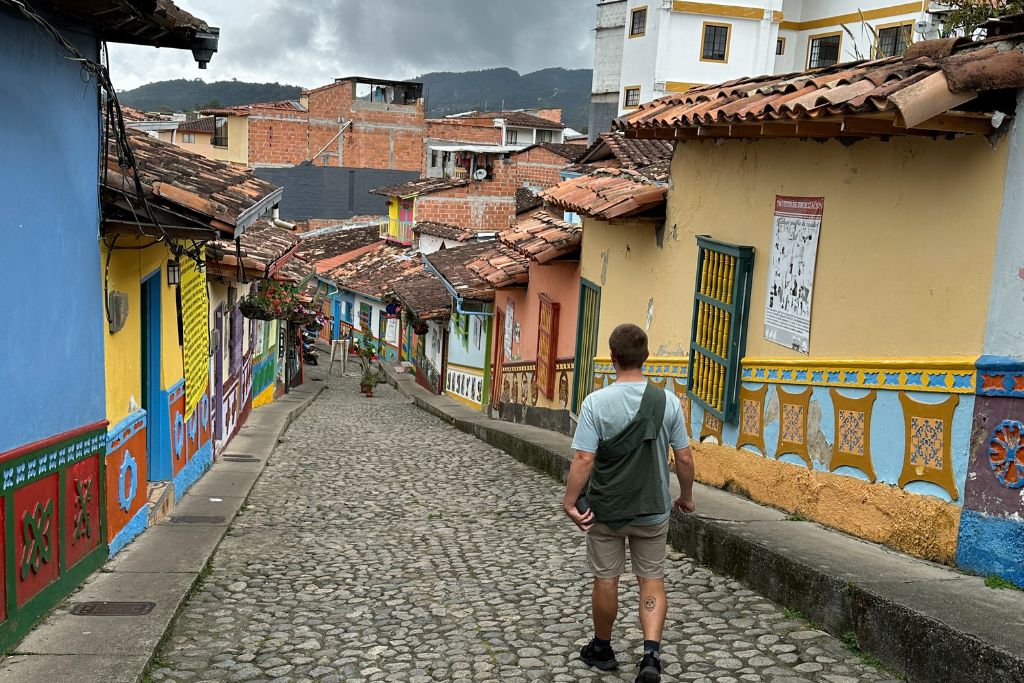 a man walking down one of the many colourful streets in guatape