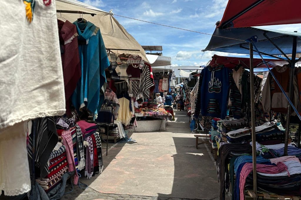 a view down a street in the Otavalo Market, with ponchos and other textiles
