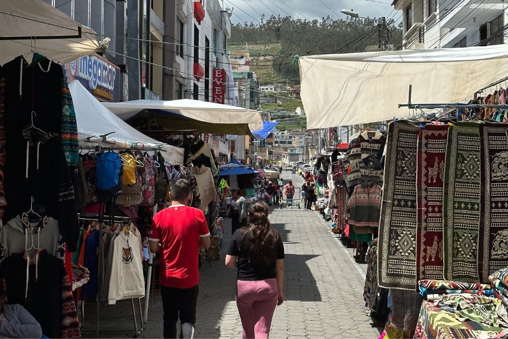 A view down a market street in Ecuador with a hill in the background