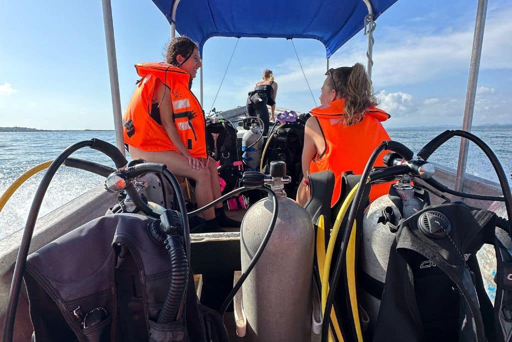 two women sitting on a boat full of diving equipment