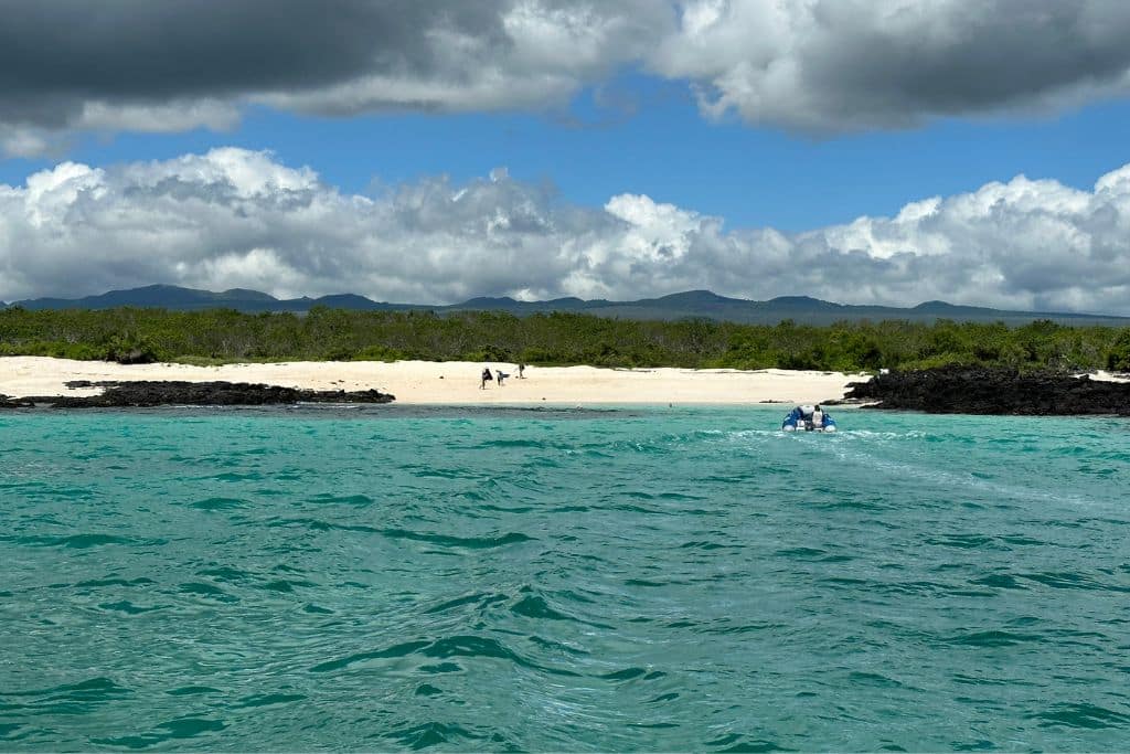 a beautiful white sand beach with turquoise water and dark grey clouds