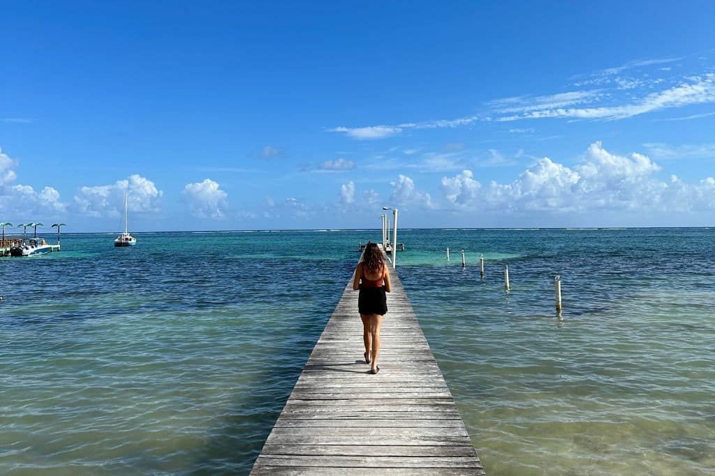 a girl walking out to sea on a long wooden pier in Belize
