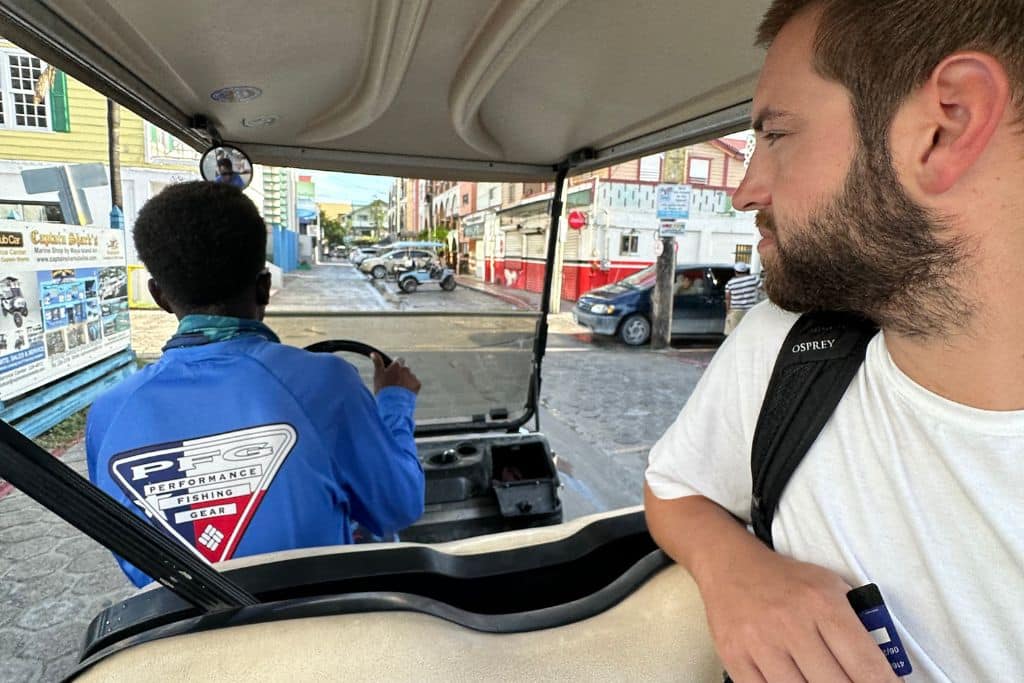 a man getting a ride in the bag of a golf cart in Ambergris Caye Belize