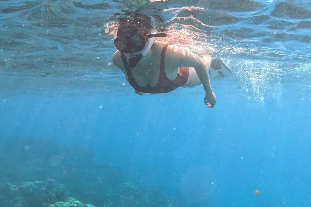 a girl snorkelling in clear blue waters in Belize